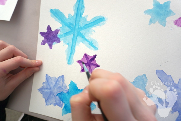 Fun to Make Watercolor Snowflakes - make fun snowflake themed painting using cookies cutters - 3Dinosaurs.com #watercolorforkids #cookiecuttes #paintingforkids #finemotorskills #winteractivitiesforkids