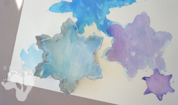 Fun to Make Watercolor Snowflakes - make fun snowflake themed painting using cookies cutters - 3Dinosaurs.com #watercolorforkids #cookiecuttes #paintingforkids #finemotorskills #winteractivitiesforkids