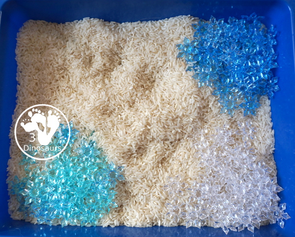 Snowflake Sensory Bin with Rice Filler - a simple sensory bin with rice for the filler and three colors of acrylic snowflakes in the sensory bin. Only a minute to set up this sensory bin. - 3Dinosaurs.com