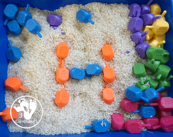 Dreidel Sensory Bin with Rice for Hanukkah - A simple Hanukkah sensory bin with dreidels and rice for the sensory bin - 3Dinosaurs.com