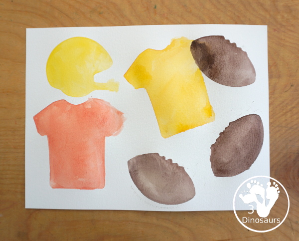 Football Cookie Cutter Watercolor Painting - a fun painting that kids can do with a football theme. A great way to do a fun watercolor painting is by different football team colors. - 3Dinosaurs.com
