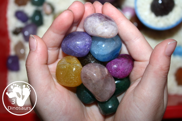 Rock & Rice Sensory Bin - Holding rocks in their hands from the sensory bin. - 3Dinosaurs.com