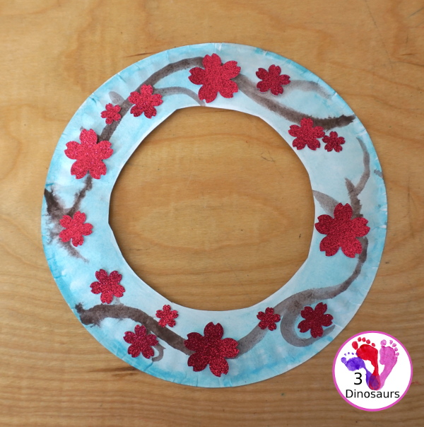 Cherry Blossom Wreath is a great spring wreath that kids can make with a paper plate for the base and watercolor and cherry blossom punches for the flowers. The Cherry Blossom Wreath is perfect for spring. - 3Dinosaurs.com
