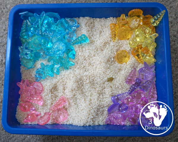 Shell and Rice Sensory Bin has a rice filler with acrylic sheets in different colors as the part in the sensory bin. This is a simple beach sensory bin idea for kids. - 3Dinosaurs.com
