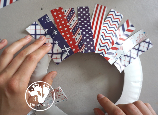 Red White and Blue Wreath Craft - a fun wreath craft made with scrapbook or any type Fourth of July paper with the red and blue themed paper around the paper plate. A simple craft you can do with preschool, prek and kindergarten age kids. - 3Dinosaurs.com