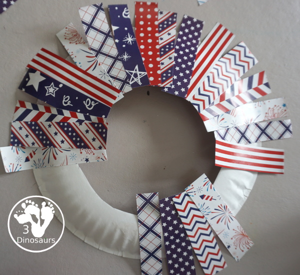 Red White and Blue Wreath Craft - a fun wreath craft made with scrapbook or any type Fourth of July paper with the red and blue themed paper around the paper plate. A simple craft you can do with preschool, prek and kindergarten age kids. - 3Dinosaurs.com
