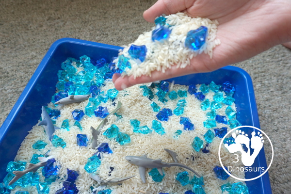 Shark Rice Sensory Bin for shark week with a mix of acrylic rocks, rice and a shark toob for the shark figures for kids to play in prek and kindergarten - 3Dinosaurs.com