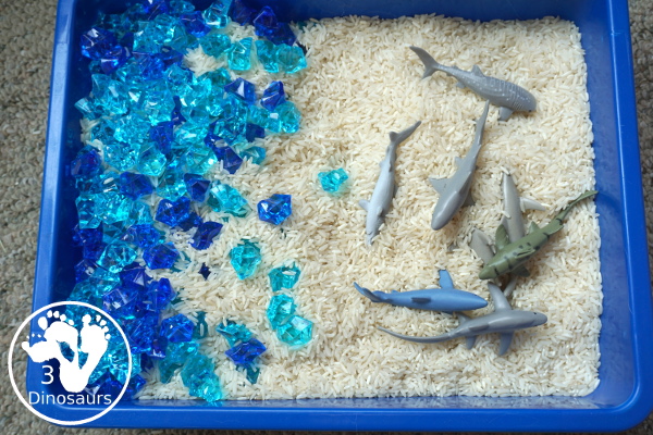 Shark Rice Sensory Bin for shark week with a mix of acrylic rocks, rice and a shark toob for the shark figures for kids to play in prek and kindergarten - 3Dinosaurs.com