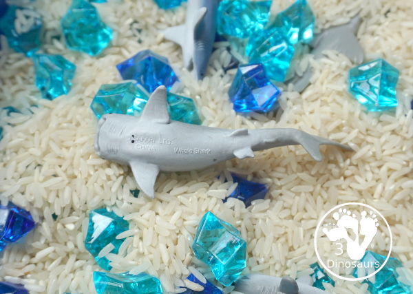 Shark Rice Sensory Bin for shark week with a mix of acrylic rocks, rice and a shark toob for the shark figures for kids to play in prek and kindergarten - 3Dinosaurs.com
