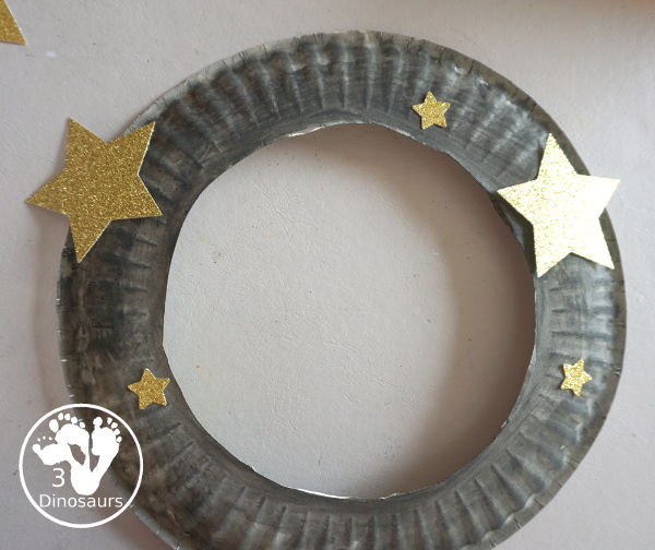 Scrapbook Paper Space Wreath Craft - a fun space craft for kids that is made with a paper plate, craft punches that are circles and stars with glitter paper and scrapbook paper. It makes a fun space craft. - 3Dinosaurs.com